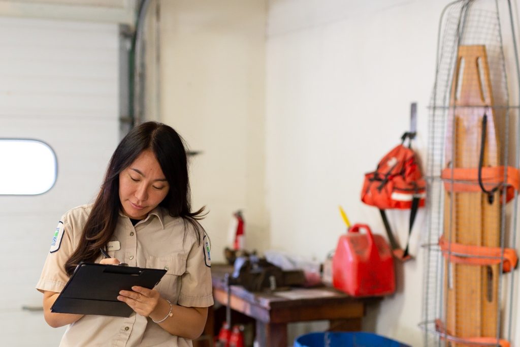 A staff member writing something down on a clipboard inside a maintenance building