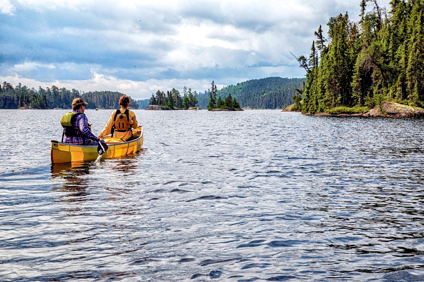 two people paddling in yellow canoe on lake