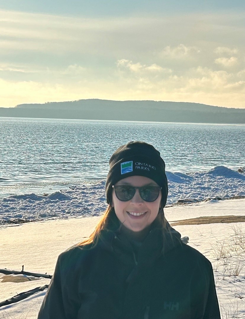 staff standing in front of beach, wearing toque