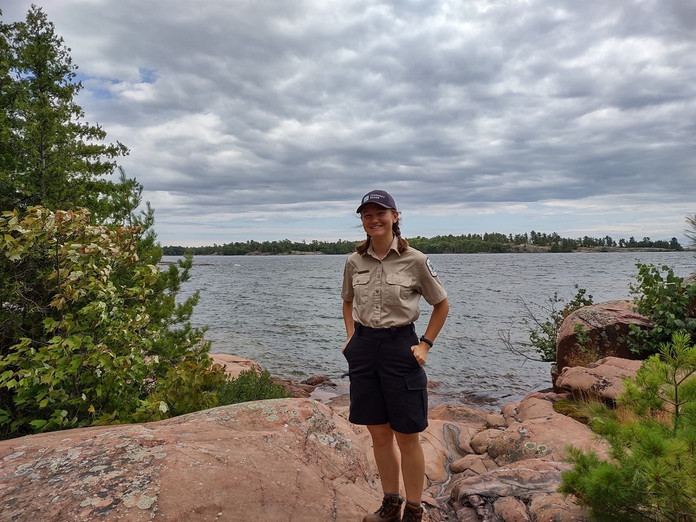 staff standing on rock formation, lake view in background