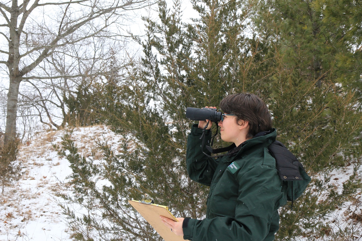 Tanya holding binoculars and clipboard, doing research at Pinery