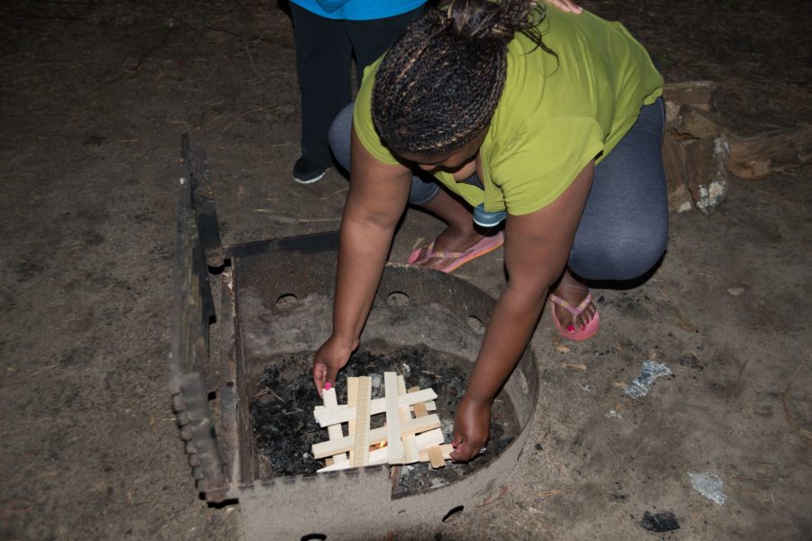 woman adding wood to campfire 