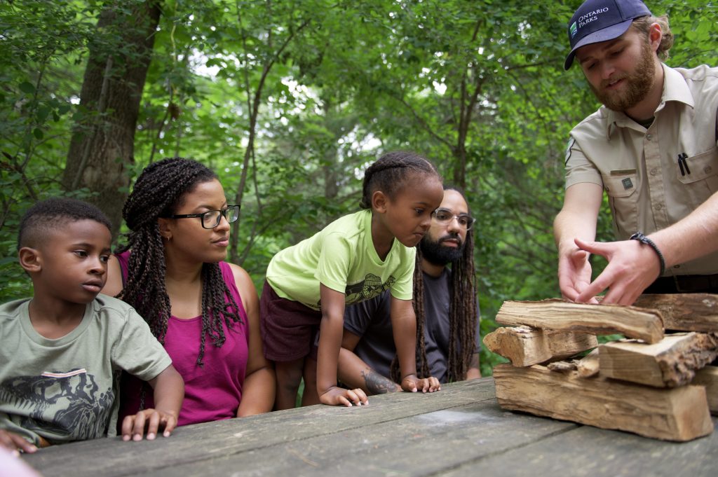Discovery staff teaching family how to start campfire