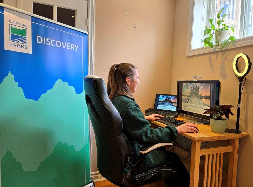 Park staffer sitting in front of a computer screen giving a presentation.