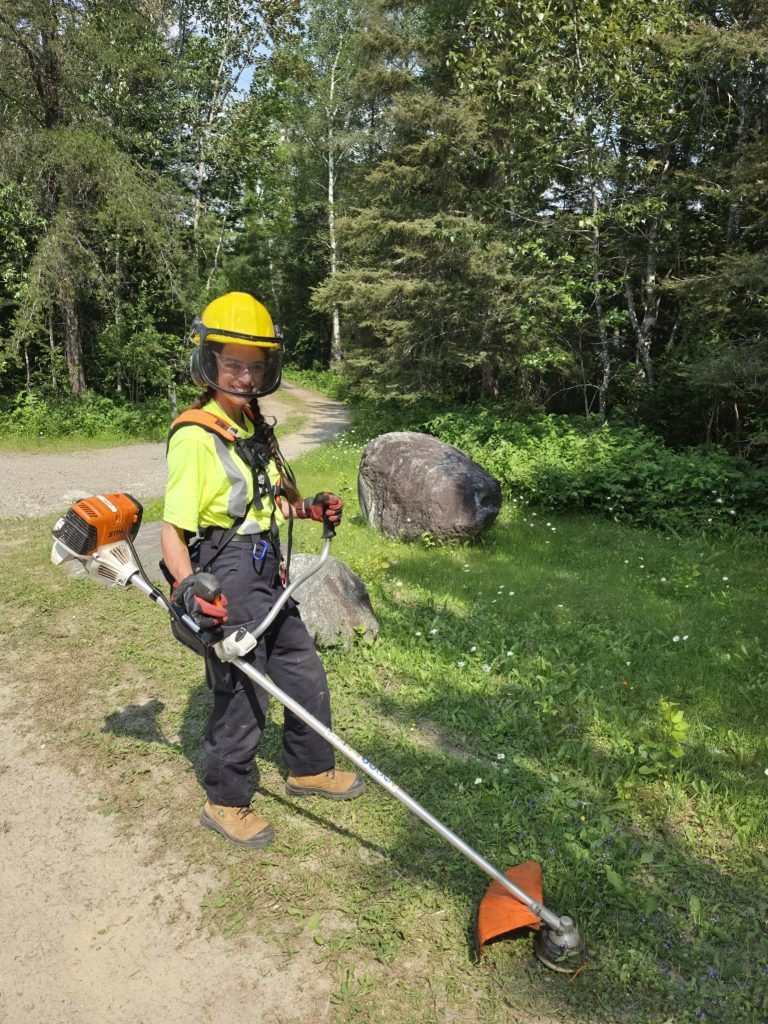 Jaren holding edge trimmer on grassy area of park
