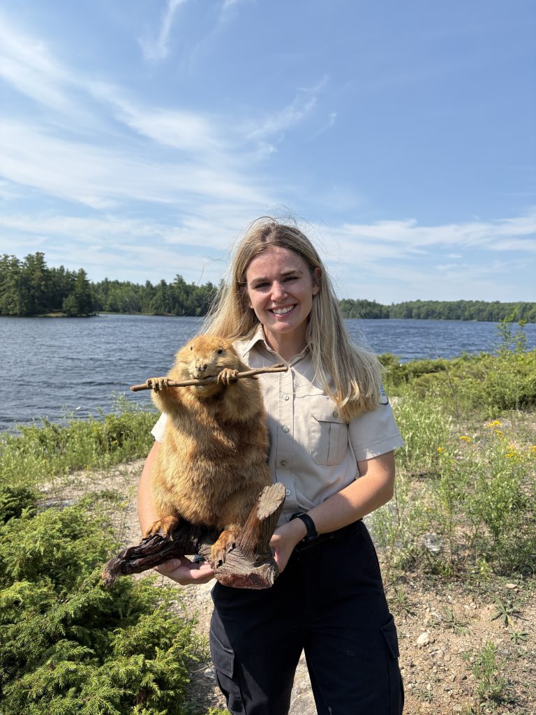 Rachel holding taxidermized beaver near body of water