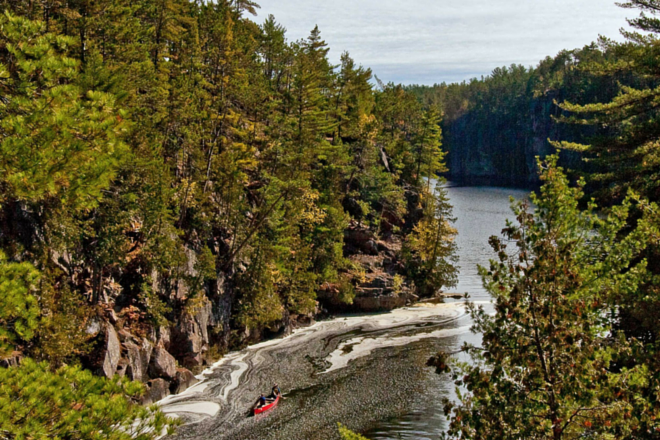 river between forest cliffs with canoe