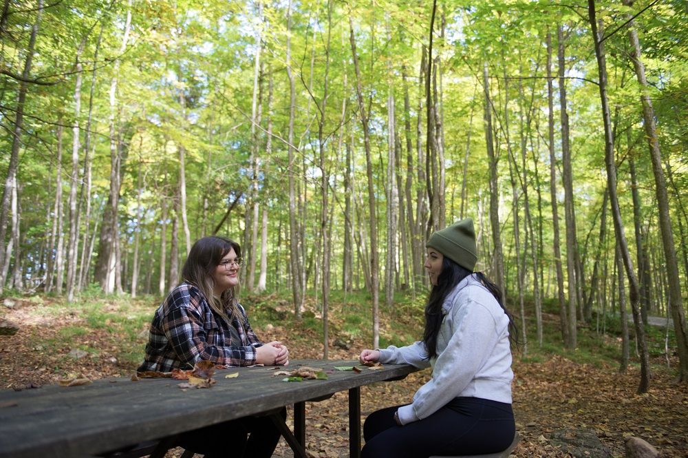  two females sitting at picnic table on campsite