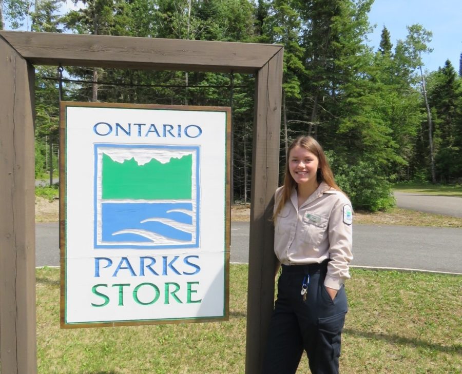 ranger standing beside park sign