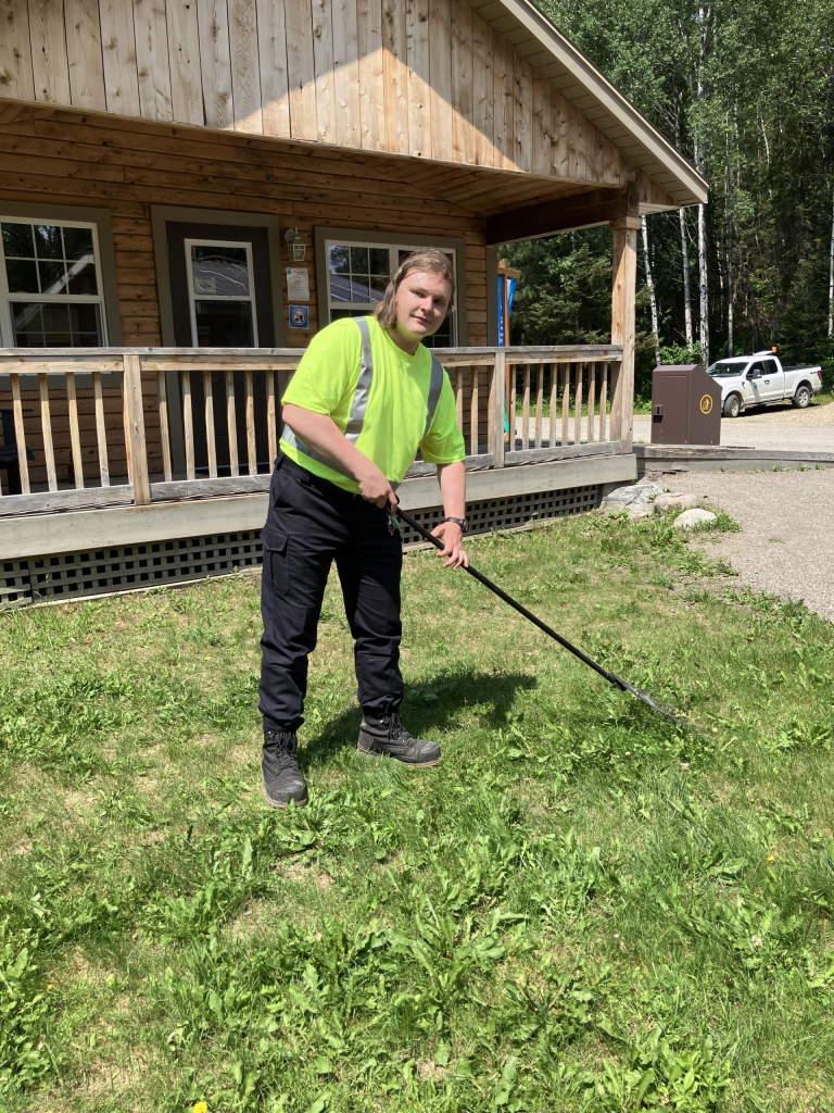 Karl en train de ratisser la pelouse à l’extérieur d’un bâtiment