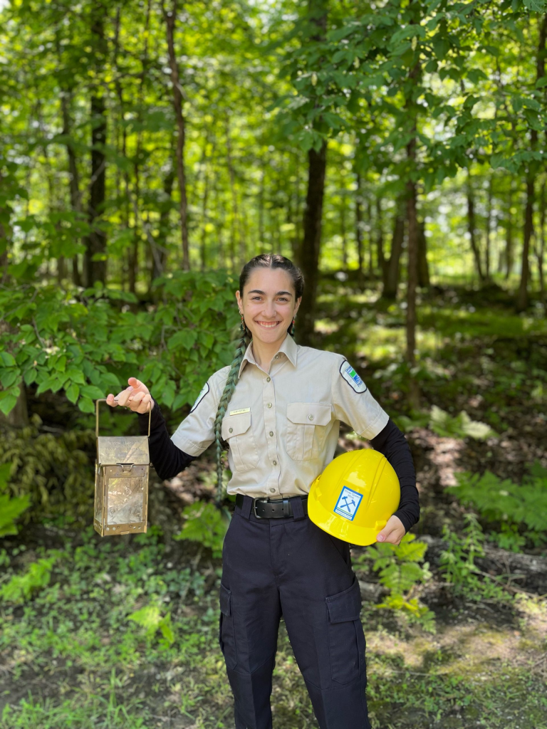 Cristal tenant une lanterne et un casque de protection, dans une forêt