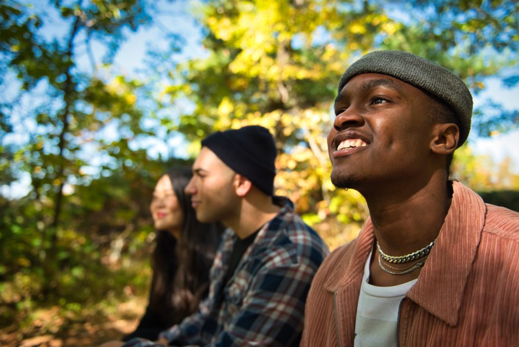 Three people resting in a fall forest.