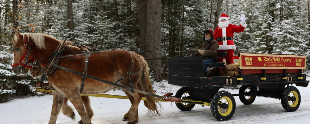 horse-drawn wagon in snow with Santa riding in the back