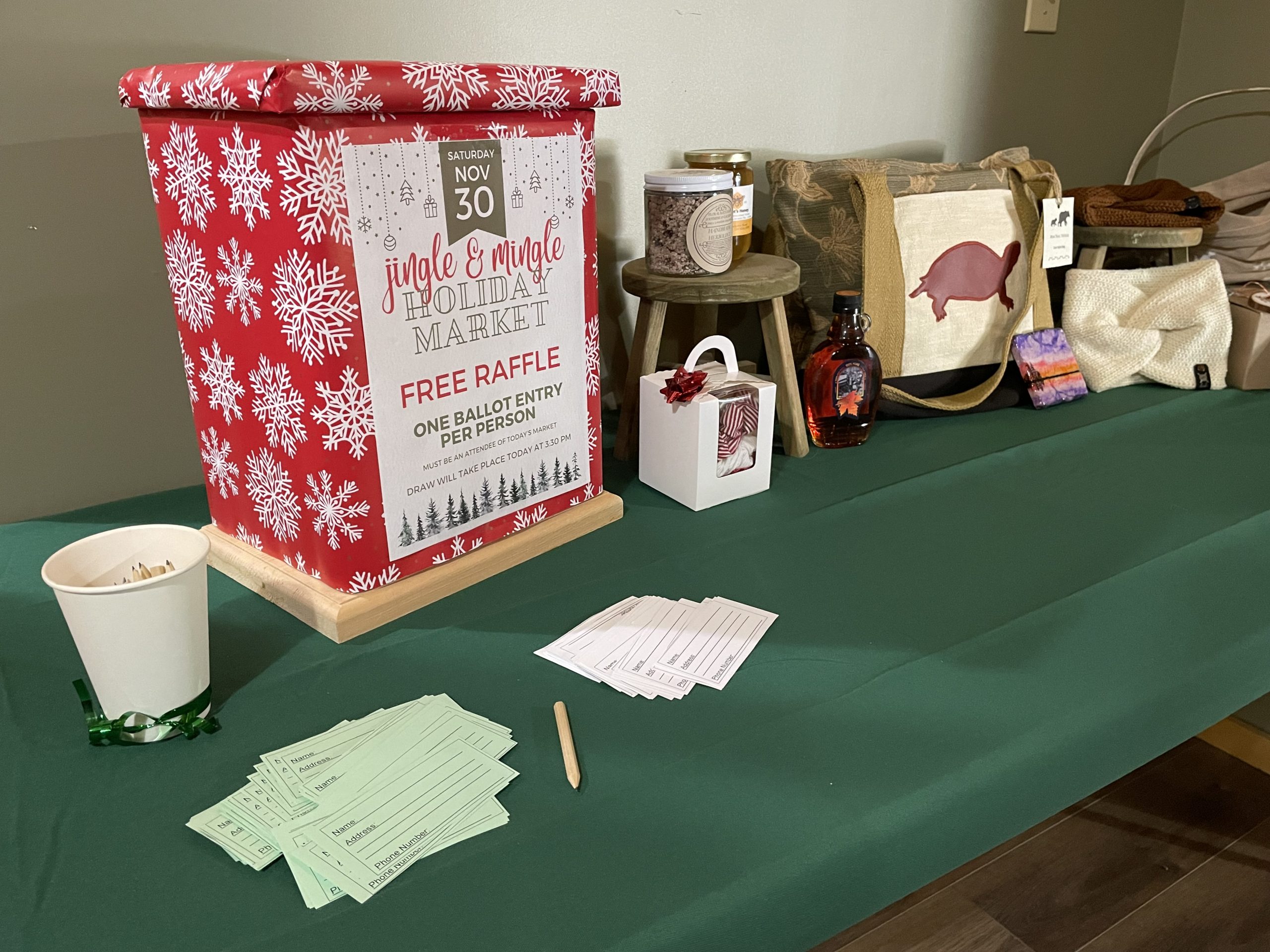 The ballot box for the Jingle & Mingle Holiday Market raffle, with the prizes beside it