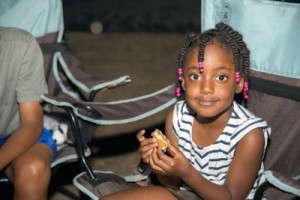 girl eating around campfire