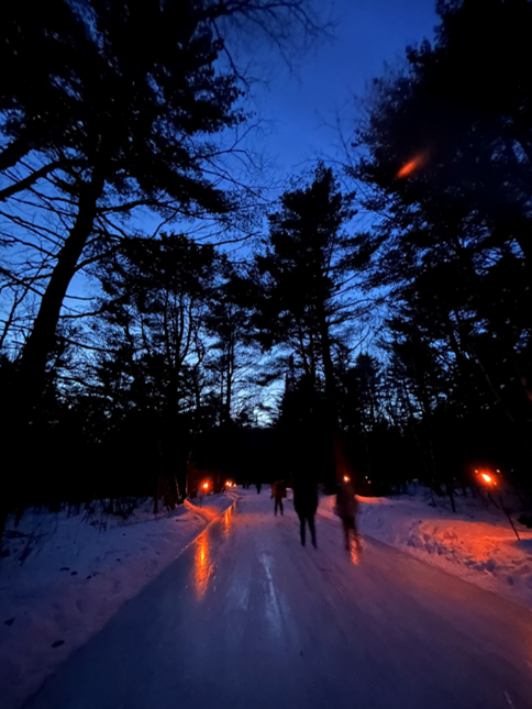 skaters on ice trail at night with torchlight