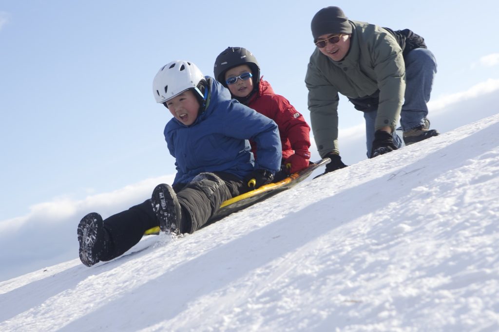 family sledding on winter hill