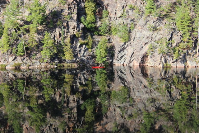 paddler beside cliffs