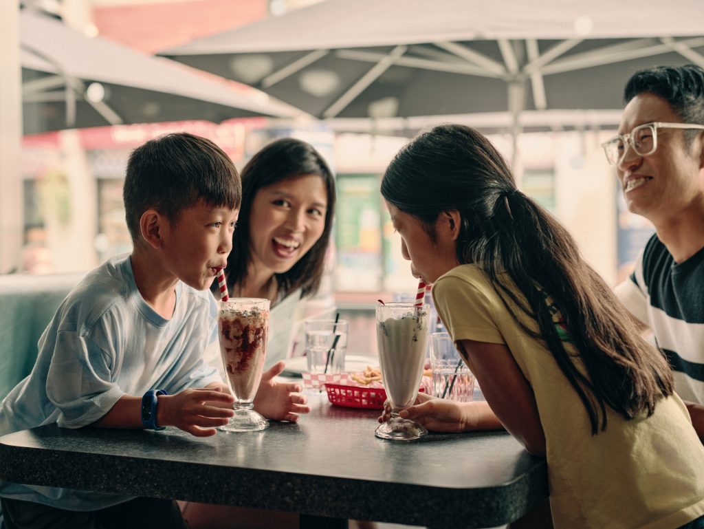 family sitting a restaurant table drinking millkshakes