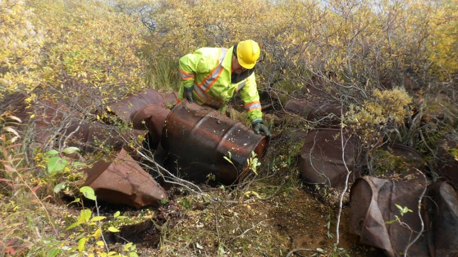 worker removing rusty drums