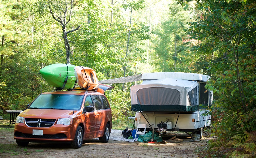 A trailer on a campsite with a vehicle with a kayak on top