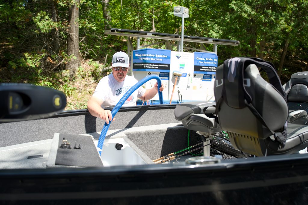boater using hose from boat wash station to drain livewell