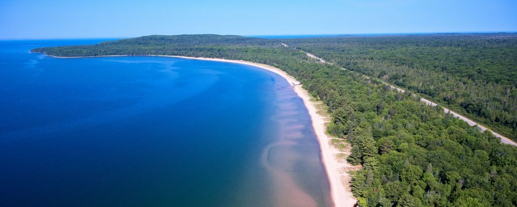 aerial view of Pancake Bay. Deep blue water surrounded by white sand beach and forest