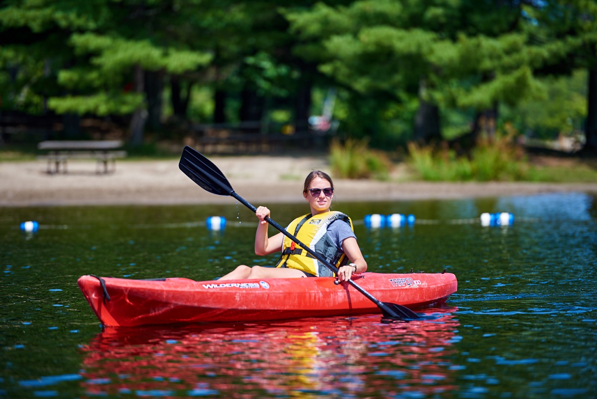 red kayak paddled by woman in lifeacket