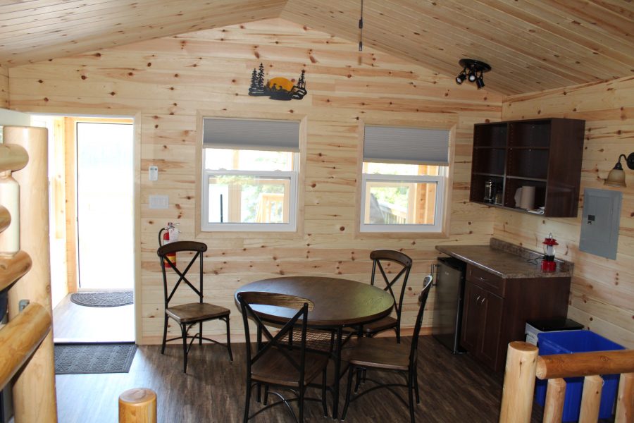 cabin interior: table, chairs, mini fridge, kitchenette