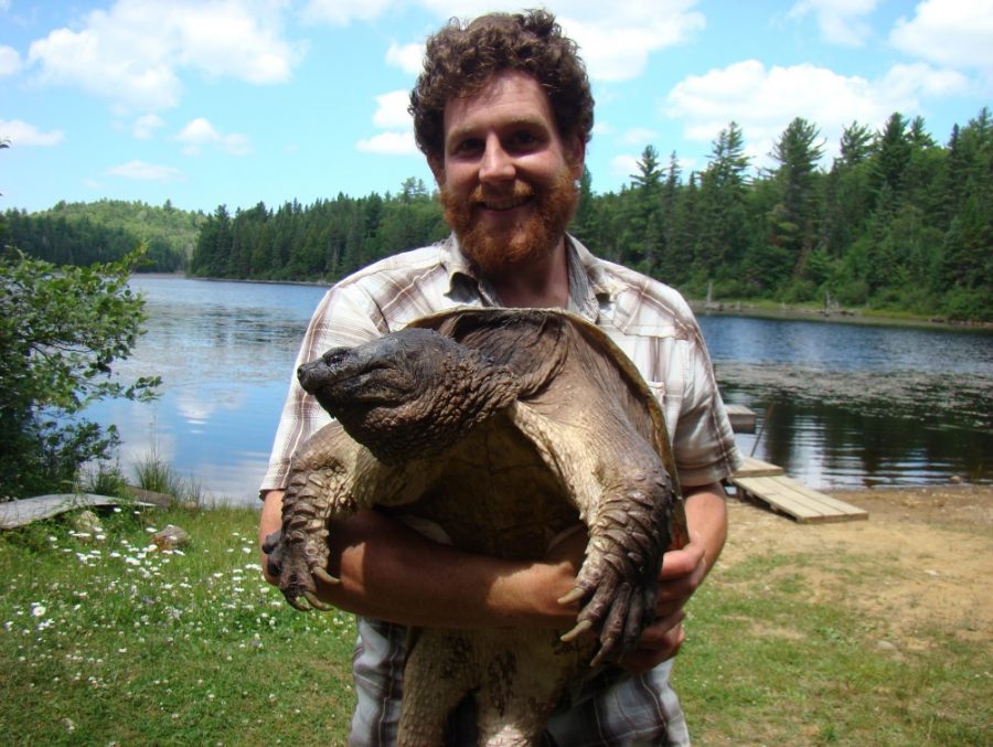 A man holds a very large snapping turtle. 