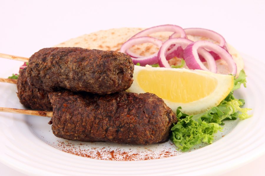 Close up of lamb kebabs and orange slice. 