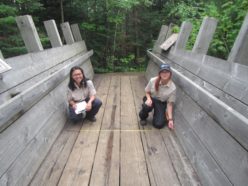 Two women crouch on a bridge