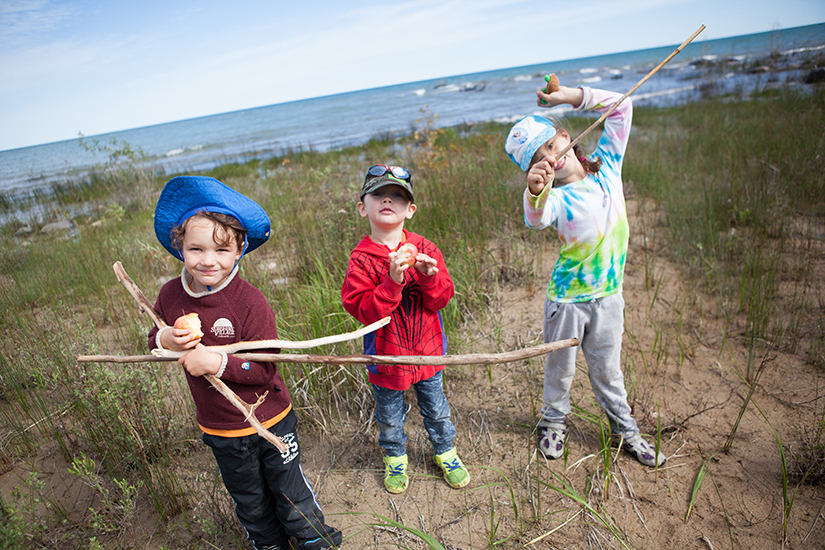 Kids pose in the sand in front of lake