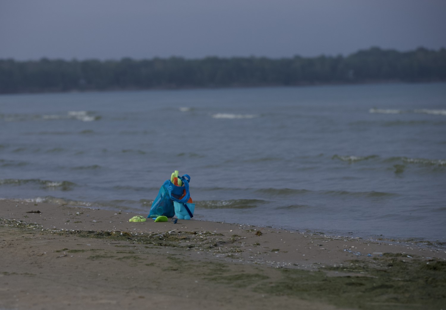 A small pile of garbage sitting in the mid-distance on a sandy beach