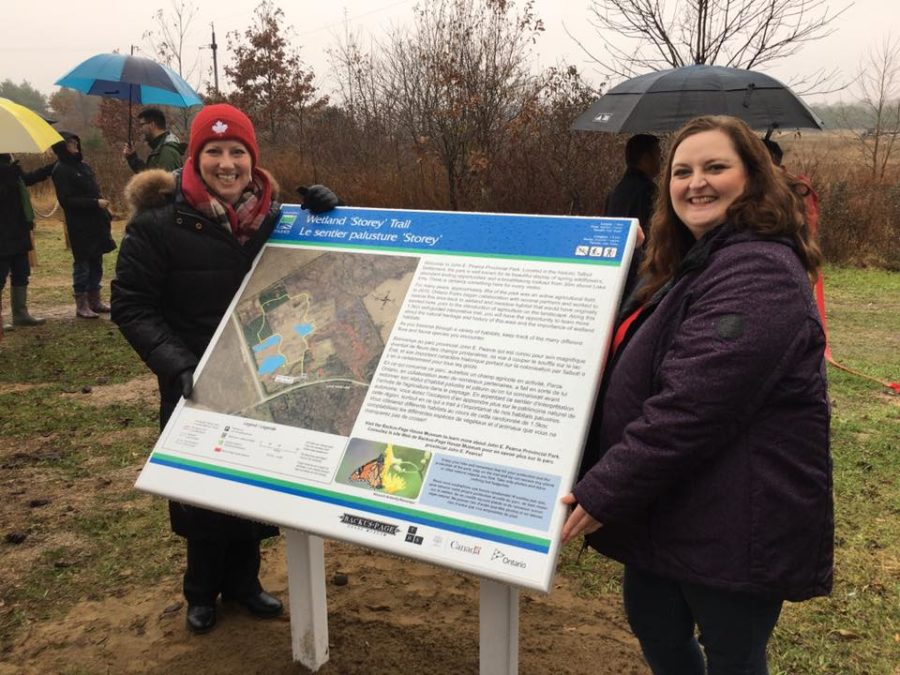 two partners standing beside trail sign