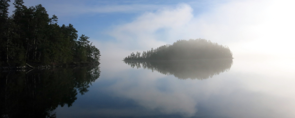 Mist on a still lake with an island in the background