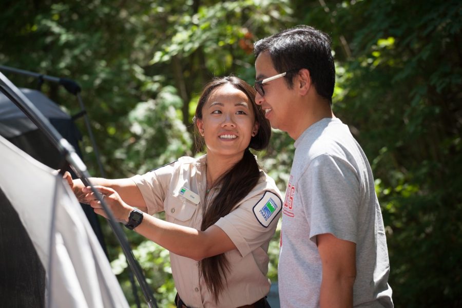 Park staff showing something not visible to a park visitor by his car