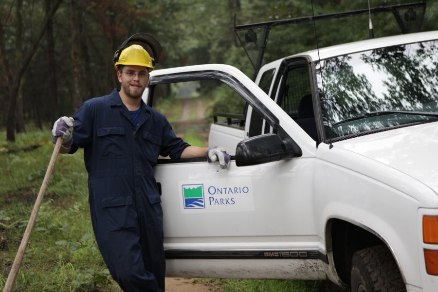 Guy with yellow hard hat standing beside white Ontario Parks truck