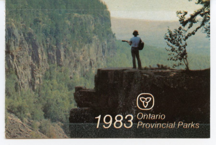 Photo of a canyon with a person standing out and looking over the canyon while playing a guitar. Text shows the trillium symbol for Ontario, and states "1983 Ontario Provincial Parks"