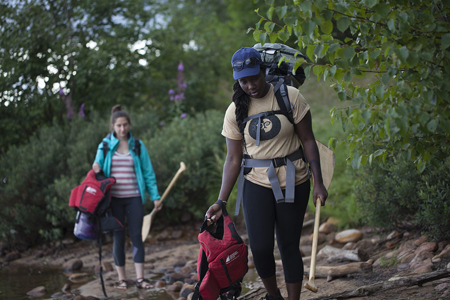 Two women carry gear