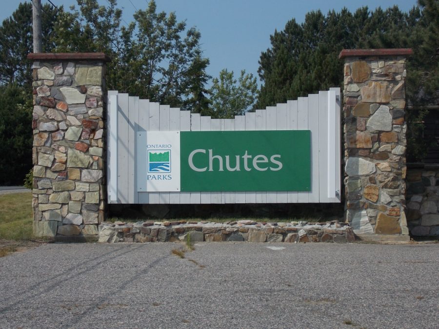 Green Ontario Parks sign with Ontario Parks logo mounted on to a white background, flanked by two stone pillars