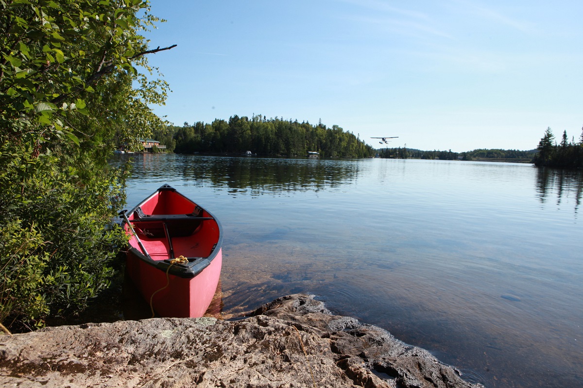 View of the lake from the rock shore with red canoe on a clearday