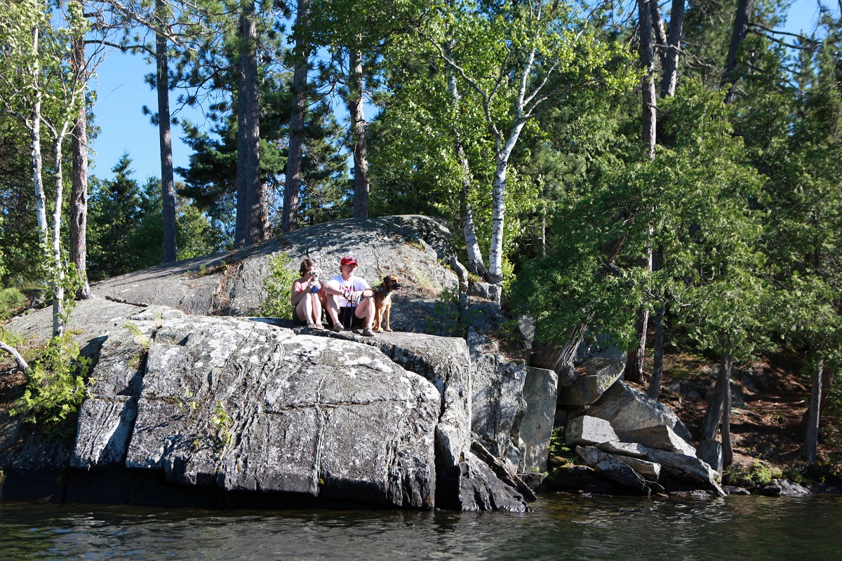 People looking at the lake from a high rock on the shore