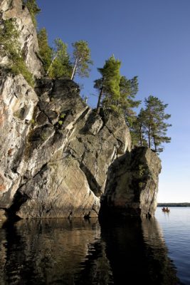 Cliff with conifers coming out of lake 