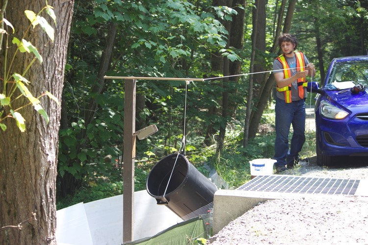 Guy with safety vest holding a string attached to a black bucket