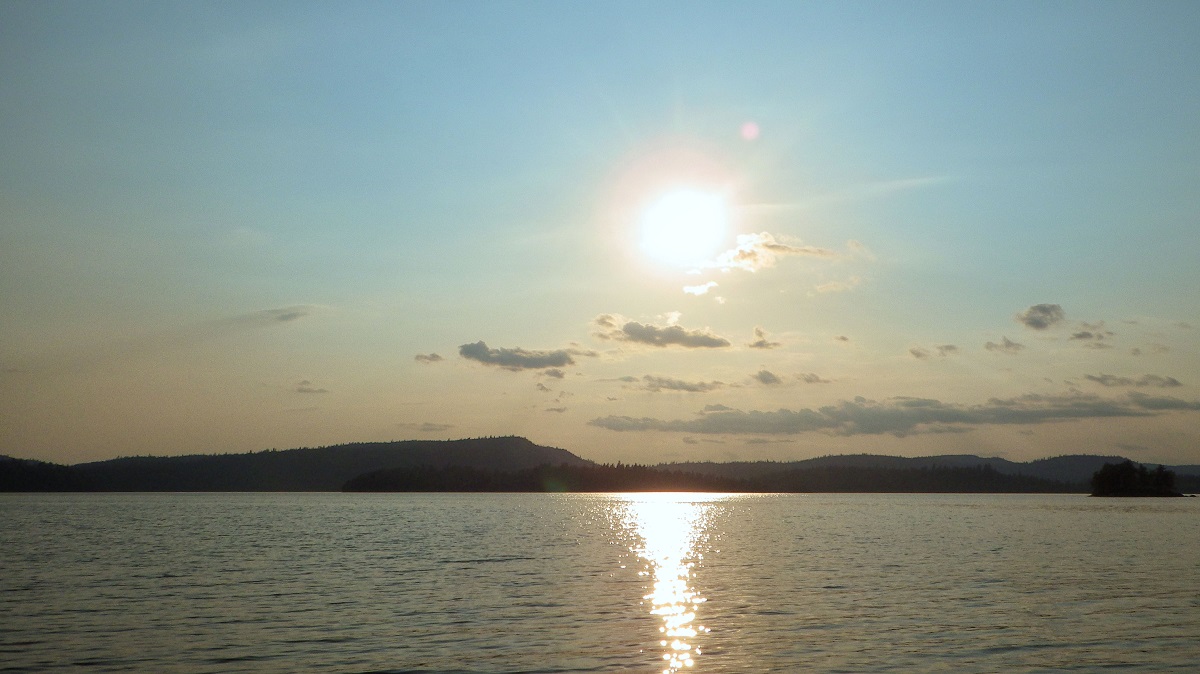 Lake with sun low in the sky reflecting in the water