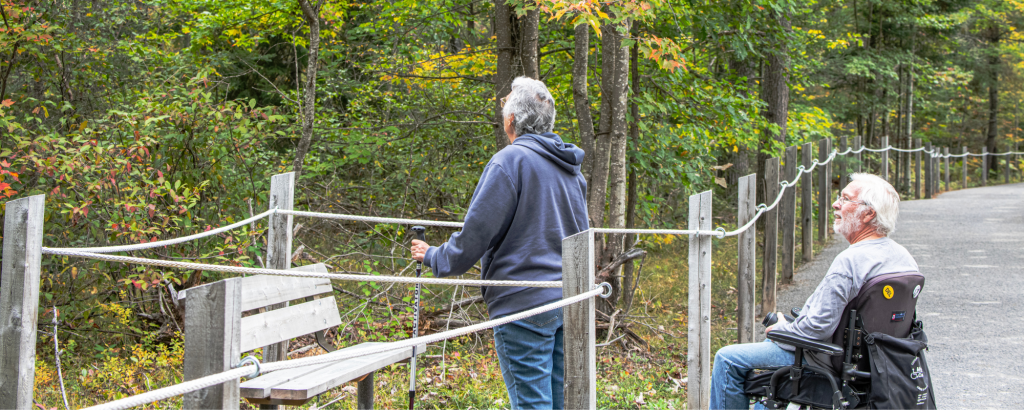 Two people on an accessible boardwalk hiking trail, looking at fall colours