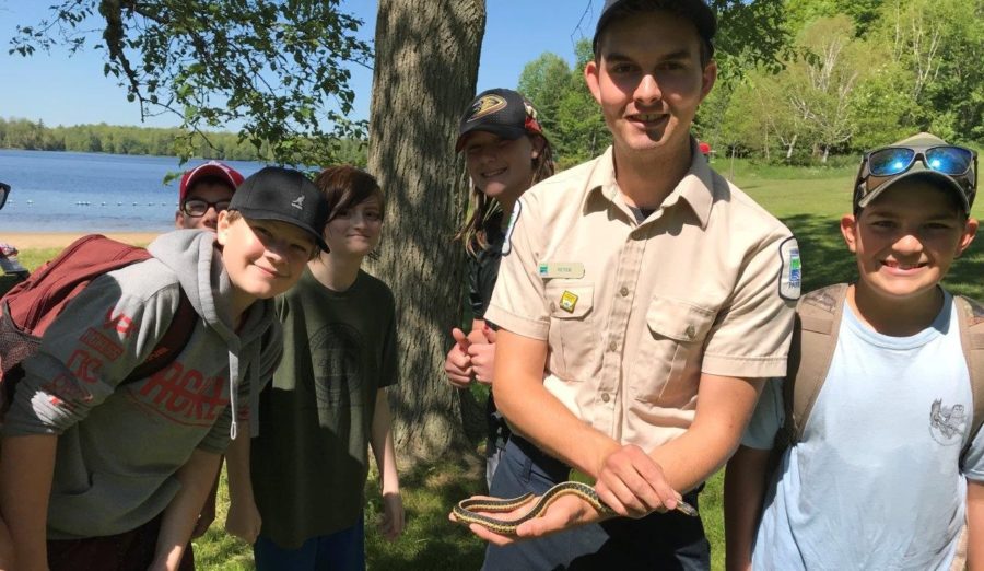 staff member holding snake, talking to students