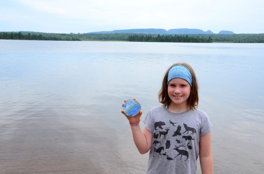 young girl holding up her cookie with lake in background