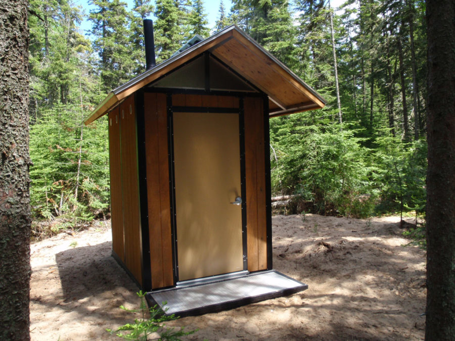 Small wooden structure with roof and single door in the woods